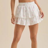 White lace skirt with floral patterns worn by a person on a beige background